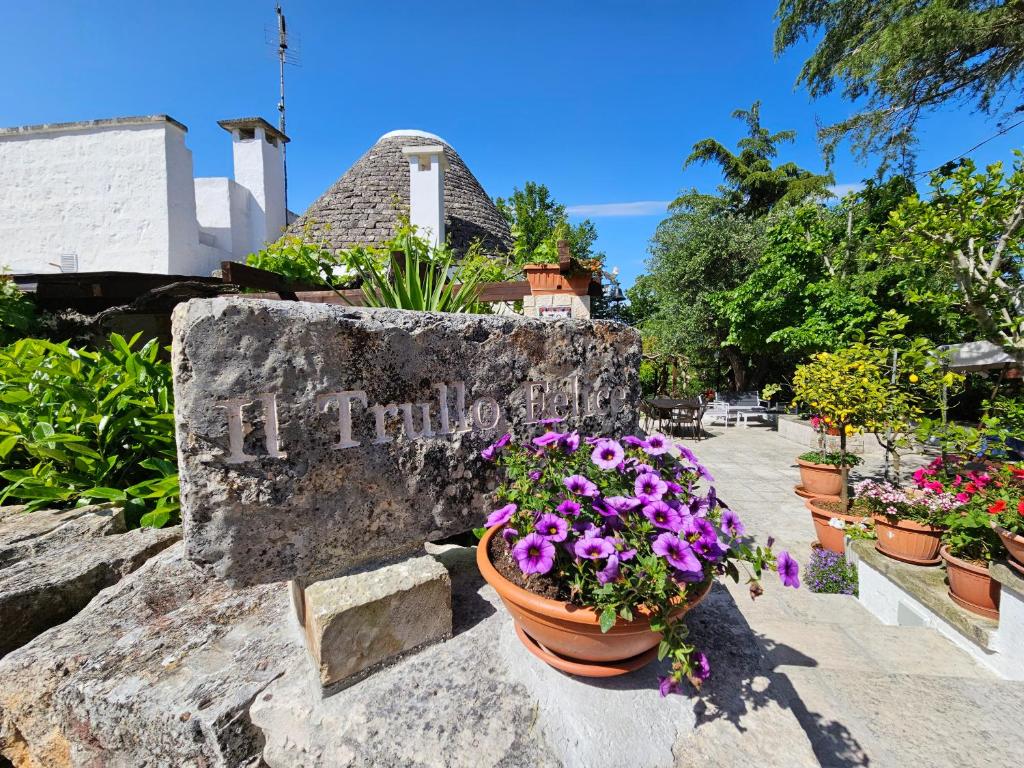 um sinal de pedra com flores na parede em Il trullo felice em Locorotondo