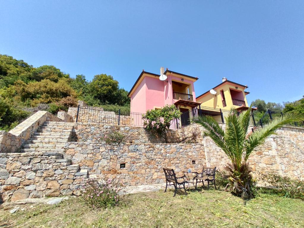 ein rosafarbenes Haus auf einer Steinmauer in der Unterkunft Katerina's Houses #2 in Alonnisos Altstadt
