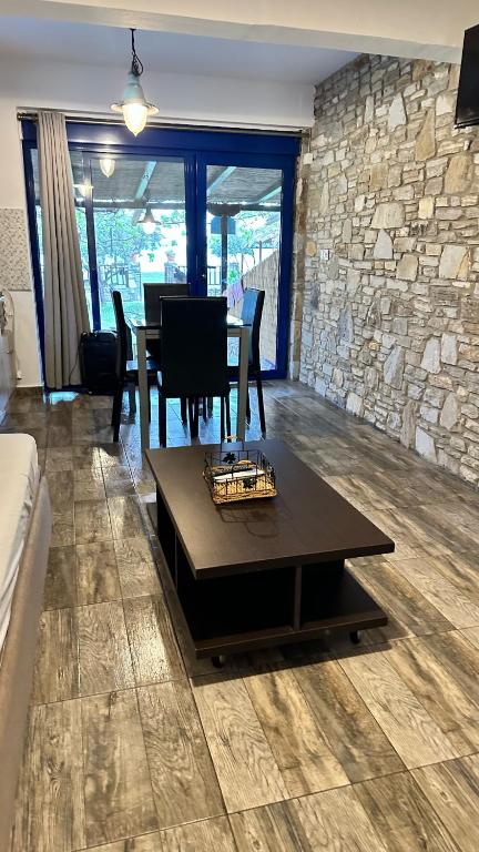 a living room with a table and a stone wall at LUUMA APARTMENT'S in Thymonia Beach