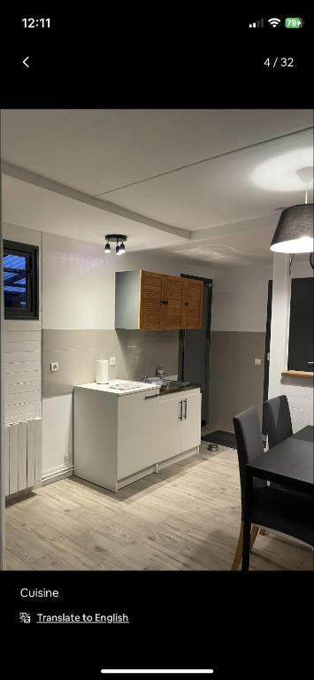 a kitchen with white cabinets and a table in a room at Petite maison chaleureuse des boucles de la Seine in Le Mesnil-sous-Jumièges