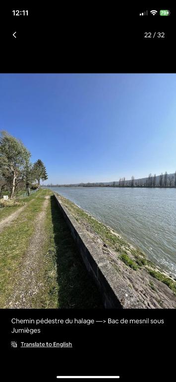 a long path next to a body of water at Petite maison chaleureuse des boucles de la Seine in Le Mesnil-sous-Jumièges