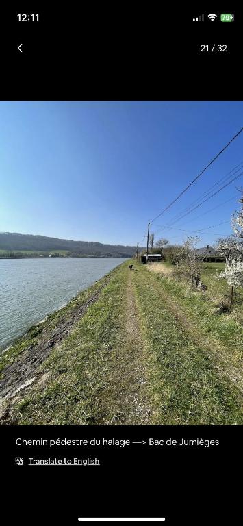 a dirt road next to a body of water at Petite maison chaleureuse des boucles de la Seine in Le Mesnil-sous-Jumièges