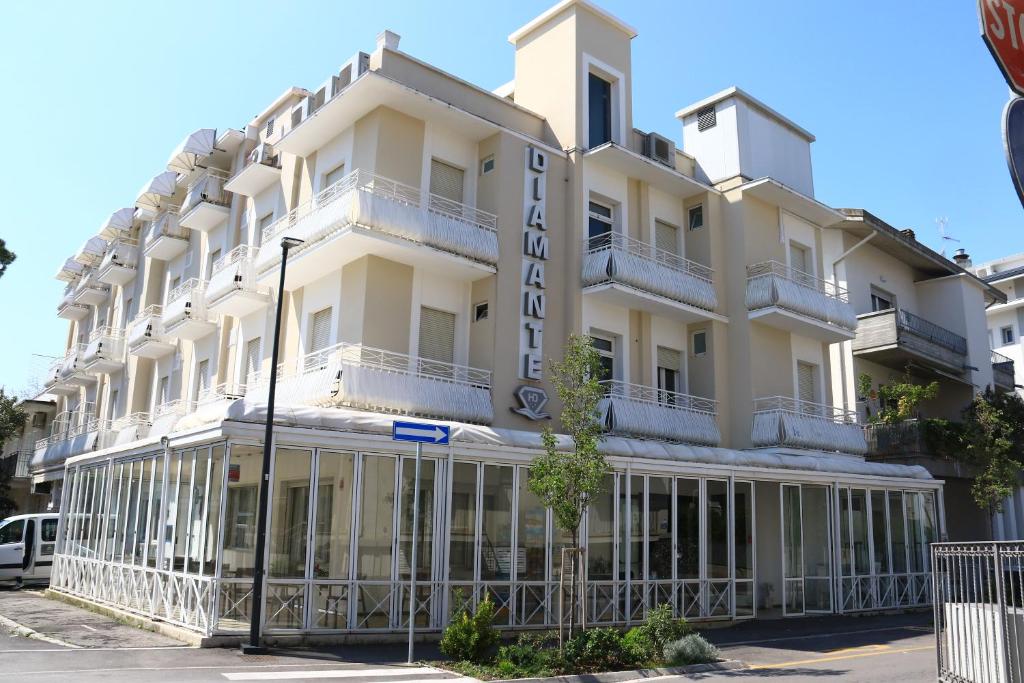 een groot wit gebouw met balkons aan een straat bij Hotel Diamante in Cattolica