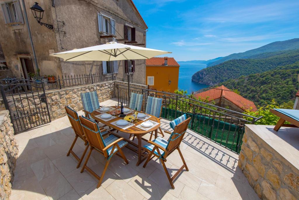 a patio with a table and chairs and an umbrella at House Bajota with terrace and sea view in Beli