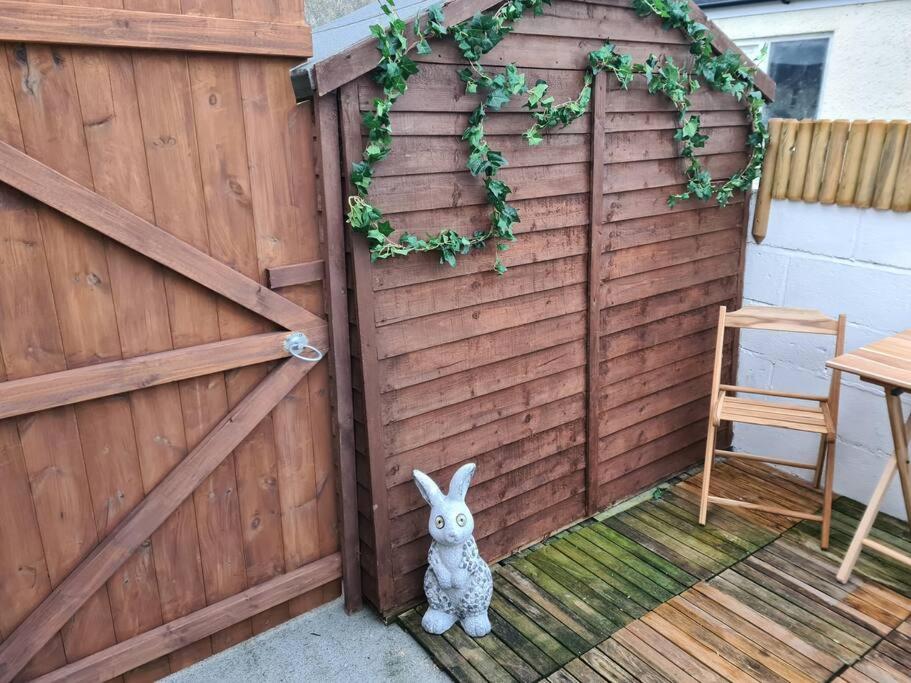 a wooden privacy fence with a rabbit standing next to a door at Sunset Place in Lower Boscaswell