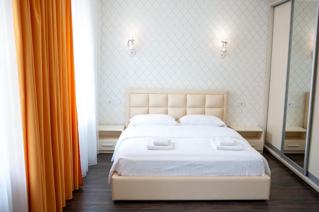 a bedroom with a white bed and orange curtains at ASAO-Apartments walking center zone in Lviv