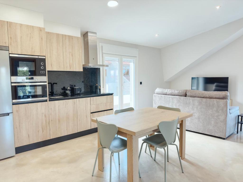 a kitchen and dining room with a wooden table and chairs at Apartamentos Avenida Areas in Sanxenxo