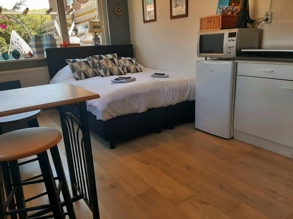 Cet appartement comprend une chambre avec un lit et une table ainsi qu'une cuisine. dans l'établissement Tuinhuis Duinroos Deluxe, à Callantsoog