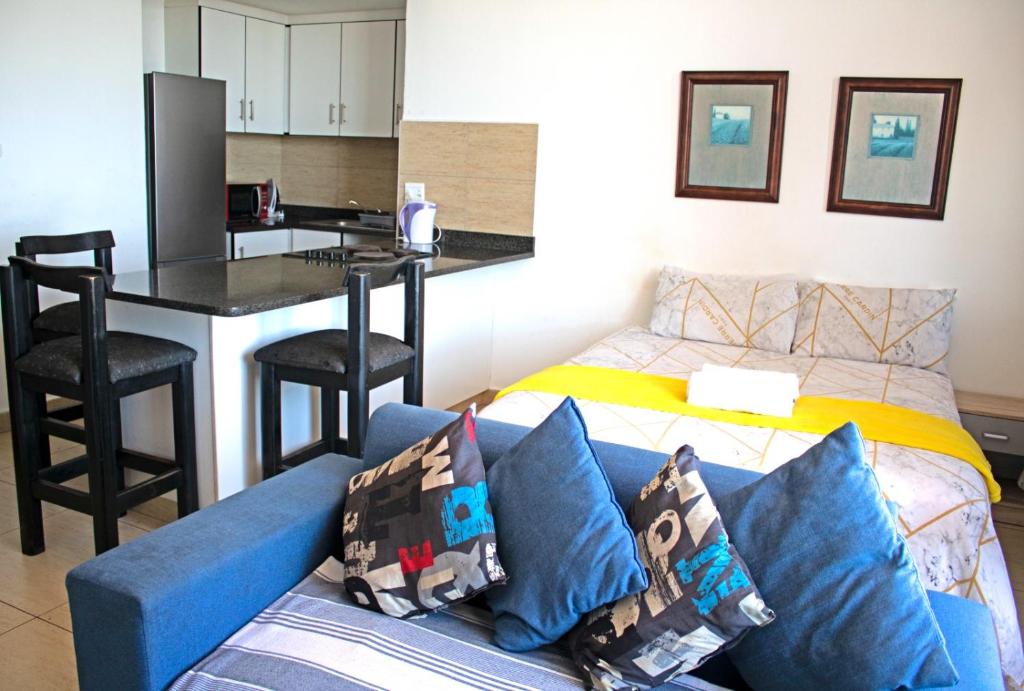 a living room with a blue couch and a kitchen at Unit 104 @Tenbury in Durban