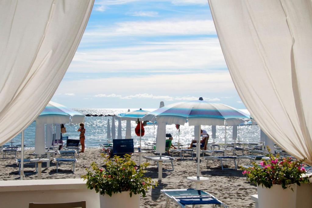 einen Strand mit Liegestühlen und Sonnenschirmen und dem Meer in der Unterkunft Pagoda 15 - Appartamento fronte mare con servizio spiaggia in Lido di Pomposa