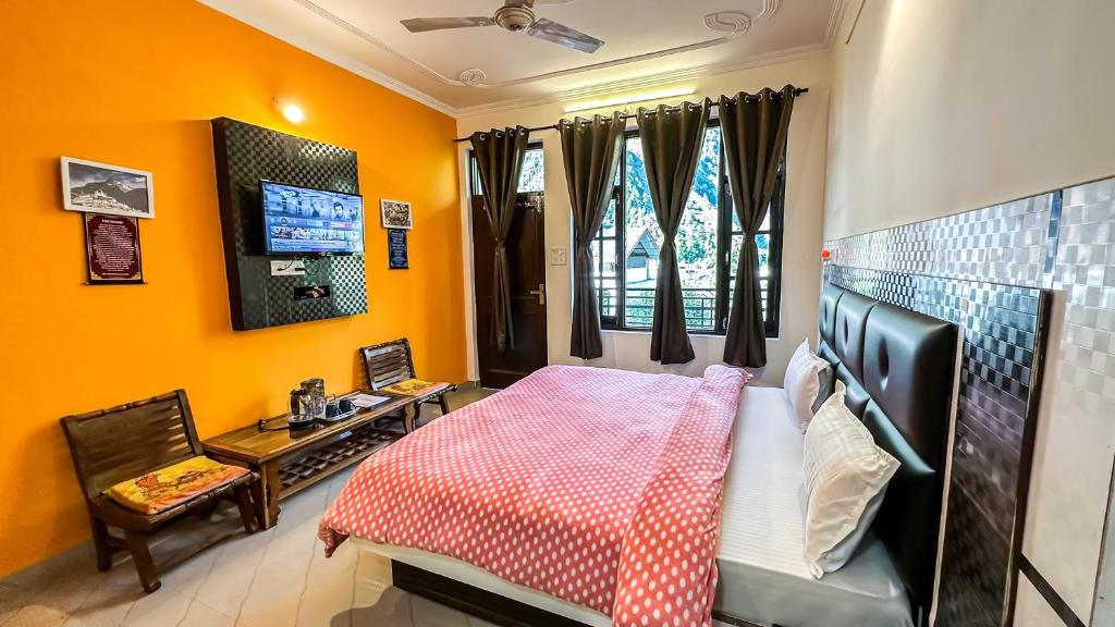 a bedroom with a bed and a desk and a tv at Mountain Vista in Dharamshala