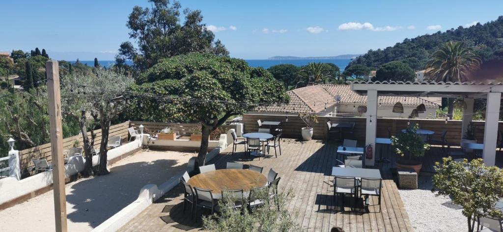 une terrasse avec une table, des chaises et des arbres dans l'établissement Hôtel Beau Site, au Lavandou