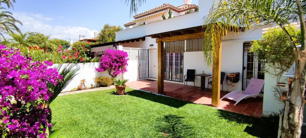 uma casa com um quintal com flores roxas em Apartamento con Jardin y Piscina en Playa em Estepona