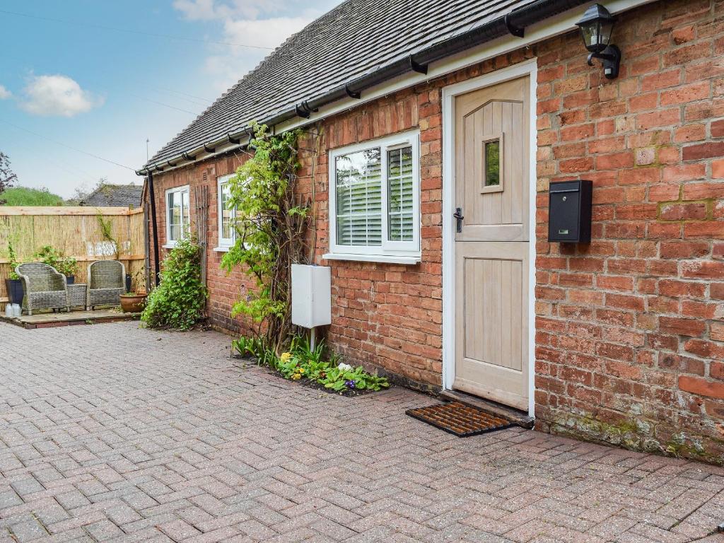 uma casa de tijolos com uma porta branca e um pátio em The Stables em Long Itchington