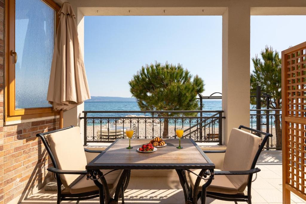 een tafel en stoelen op een balkon met uitzicht op de oceaan bij Apartments Lea in Podstrana