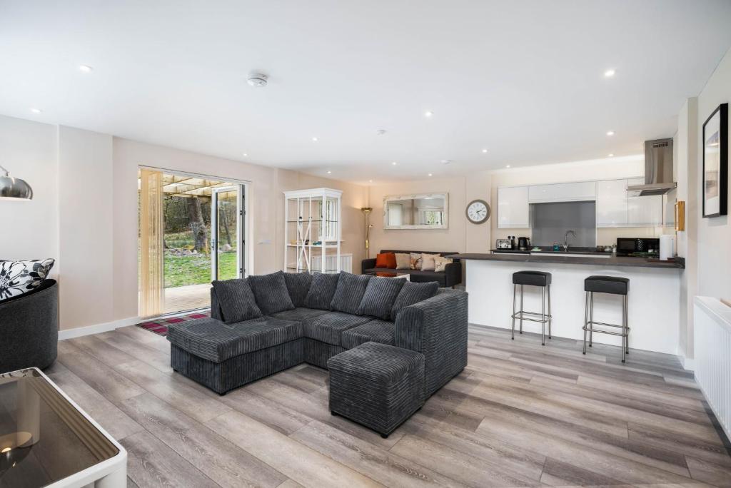 a living room with a couch and a kitchen at Westmains Lodge in Callander