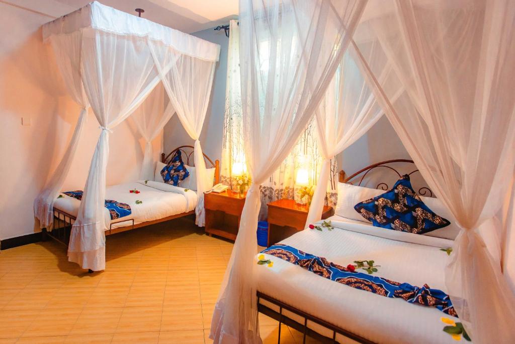 2 letti in una camera con tende bianche di Okaseni Lodge ad Arusha