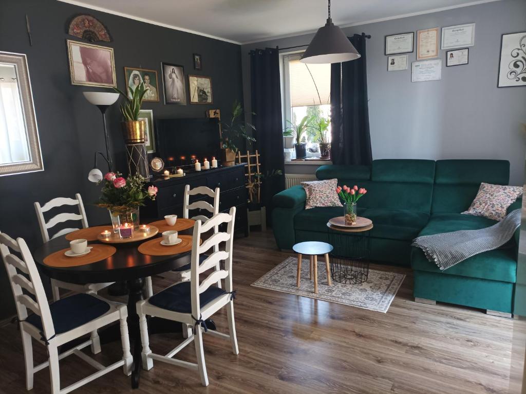 ein Wohnzimmer mit einem grünen Sofa, einem Tisch und Stühlen in der Unterkunft Atrakcyjny apartament z dużym ogrodem in Danzig
