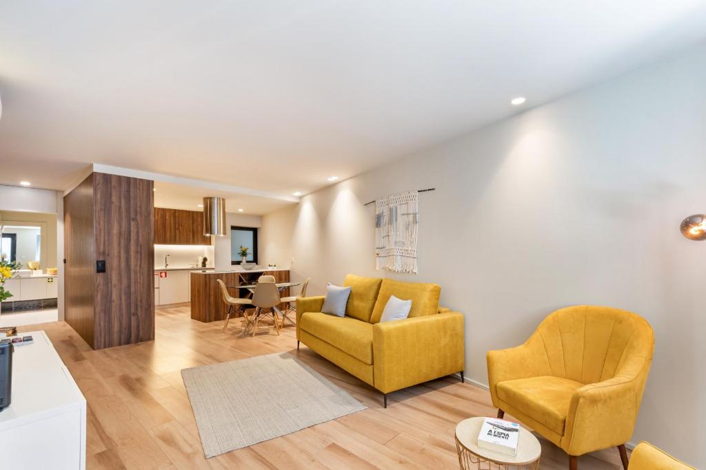 ein Wohnzimmer mit 2 gelben Stühlen und eine Küche in der Unterkunft Sé Apartamentos - São Sebastião Apartment in Braga
