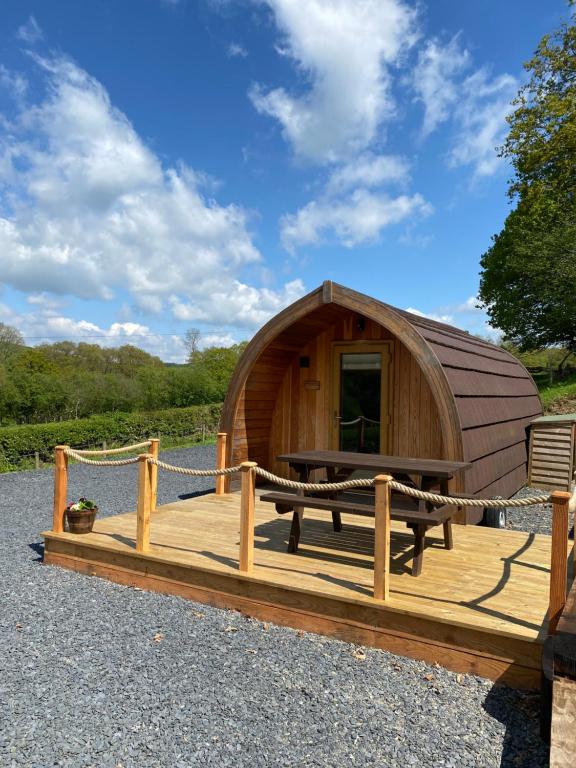 a wooden cabin with a table and a bench on a deck at Cil y Coed Luxury Pod in Machynlleth