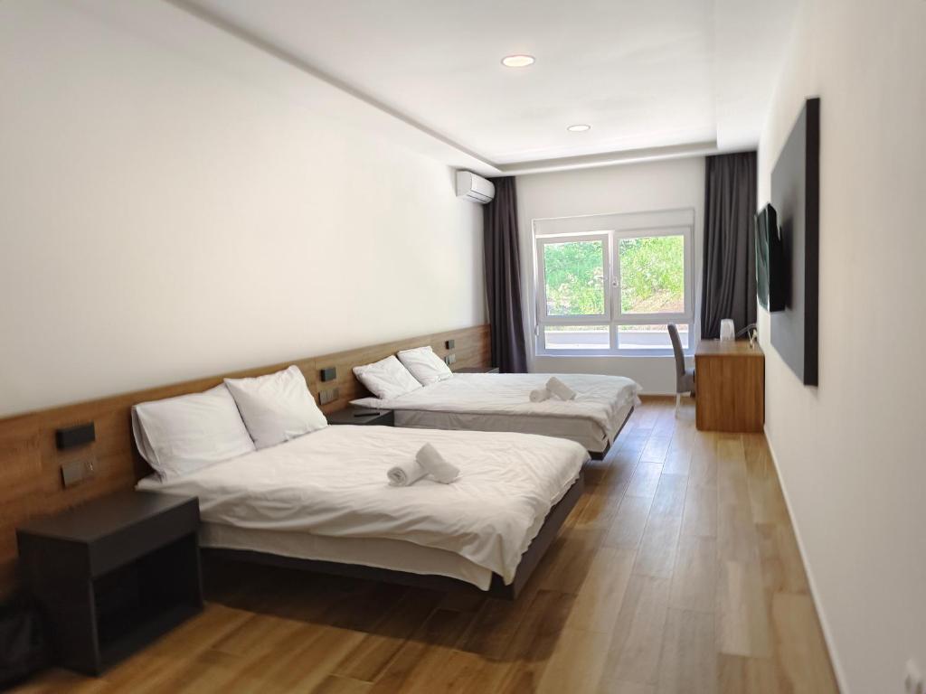 um quarto com duas camas e uma janela em H.T Hotel em Belgrado