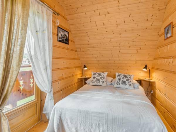 a bedroom with a bed in a wooden cabin at Domek Regionalny Bąkowo Chatka in Witów