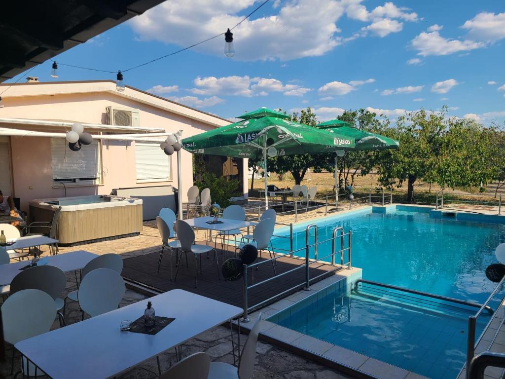 a pool with tables and a green umbrella at Hacienda Kolenda in Mostar