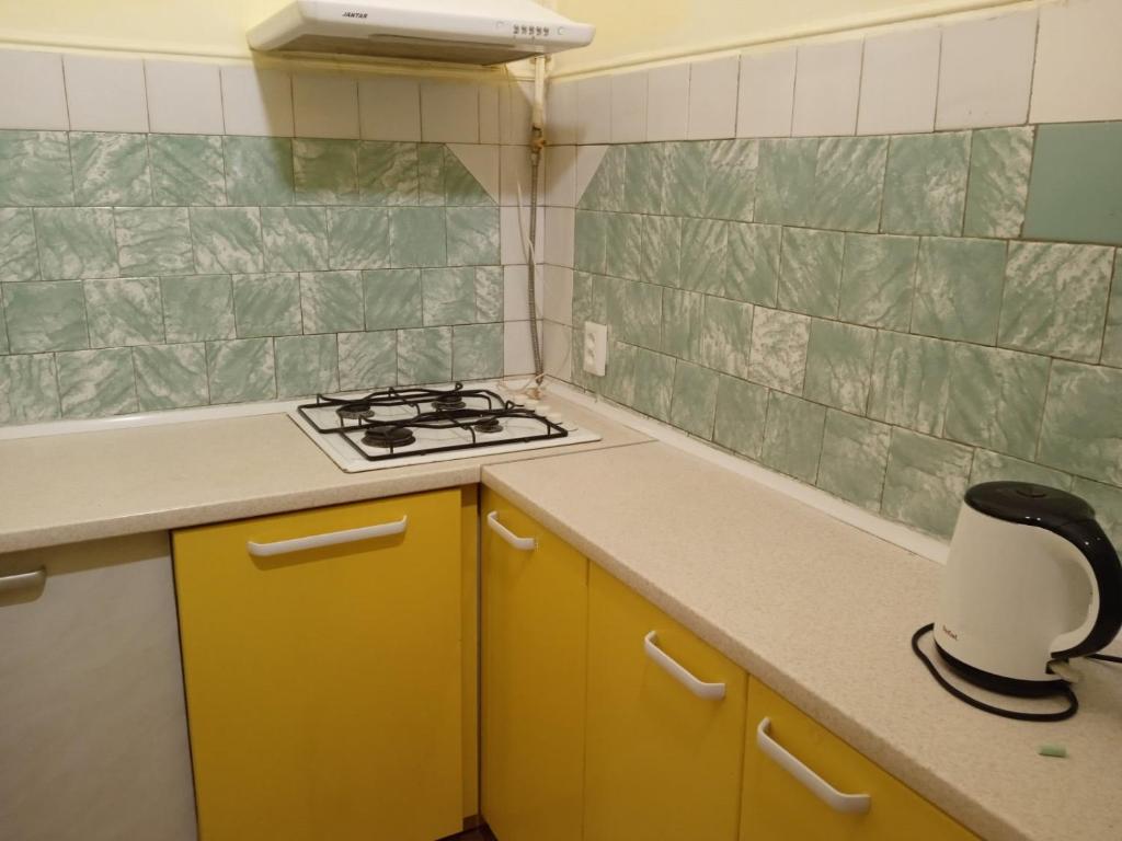 a kitchen with yellow cabinets and a stove top oven at Елітні апартаменти в історичному центрі in Chernivtsi