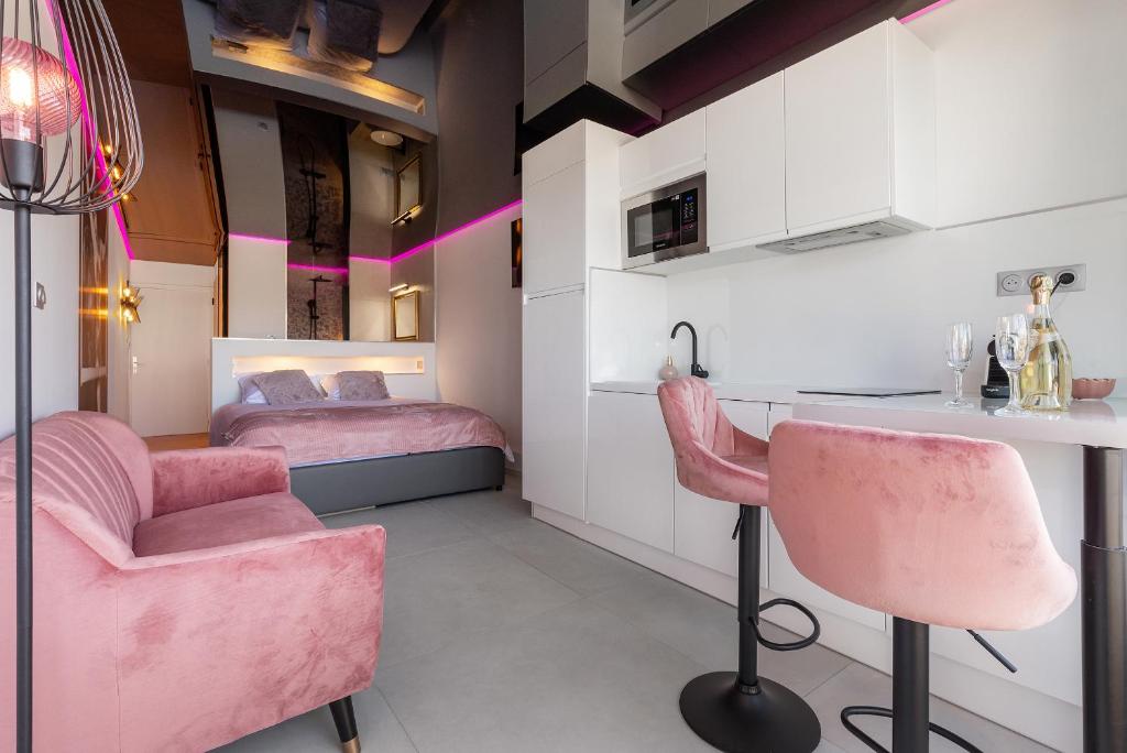 une chambre avec des chaises roses et une cuisine avec deux lits dans l'établissement Cabaret naturiste Port nature, au Cap d'Agde