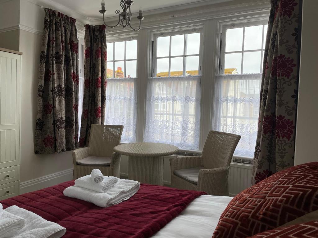 a hotel room with a bed and chairs and windows at The Sandrock in Clacton-on-Sea