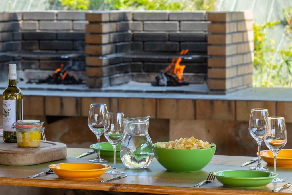 una mesa con copas de vino y un tazón de comida y una chimenea en Domaine de Saint Orens - Résidence de vacances - Montréal du Gers, en Montréal