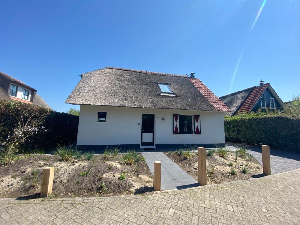 ein kleines weißes Haus mit einem Dach in der Unterkunft Villa Stilleven in Callantsoog