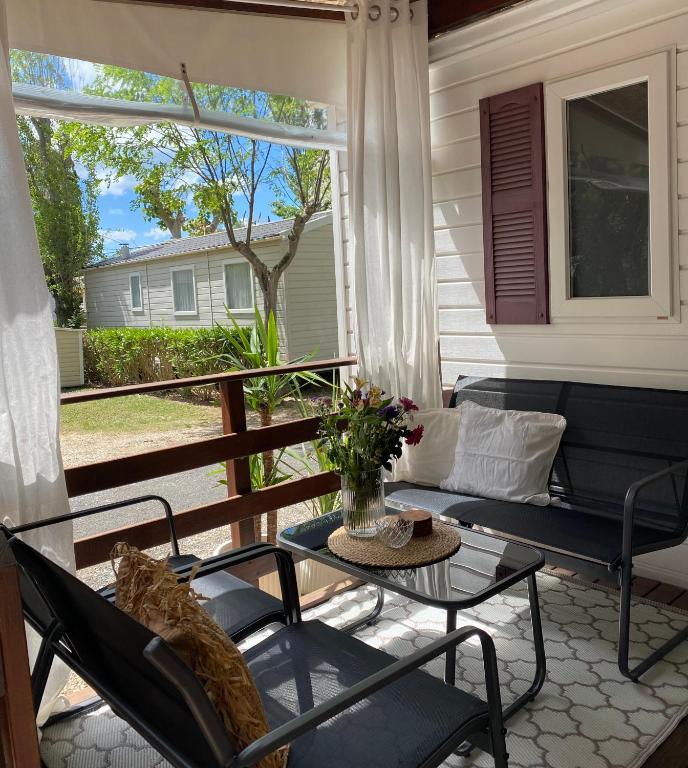 - une terrasse couverte avec une table, des chaises et un canapé dans l'établissement Ruhig gelegenes Mobilhome La Carabasse, à Vias