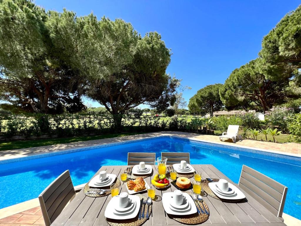 a table with food and drinks on a deck next to a swimming pool at Vilamoura Amazing Golf Villa With Pool by Homing in Vilamoura