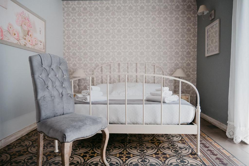 sypialnia z białym łóżkiem i krzesłem w obiekcie La Casa di Alma Luxury rooms w Katanii