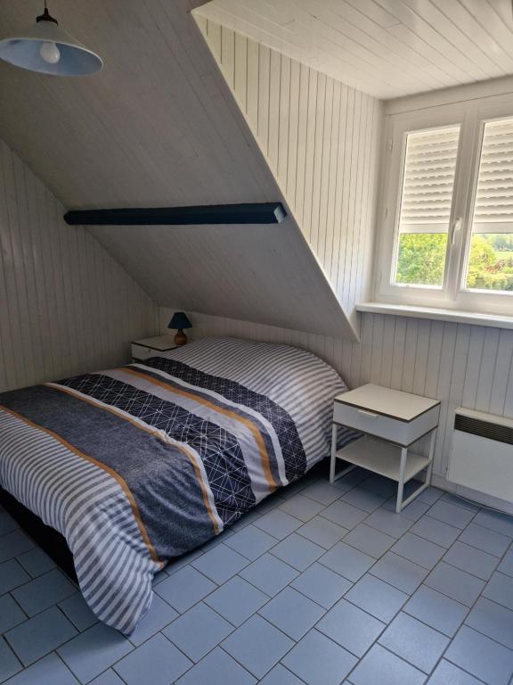 een slaapkamer met een bed, een tafel en 2 ramen bij Gite du bois des sapins in Groffliers