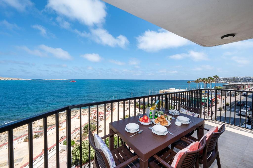a table on a balcony with a view of the ocean at Islet Promenade Seafront Apartment with large Corner Terrace by Getawaysmalta in St Paul's Bay