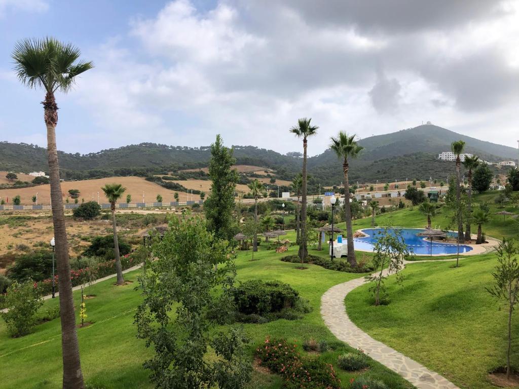 Blick auf ein Resort mit Pool und Palmen in der Unterkunft Lilacs Garden Cabo in Mʼdik