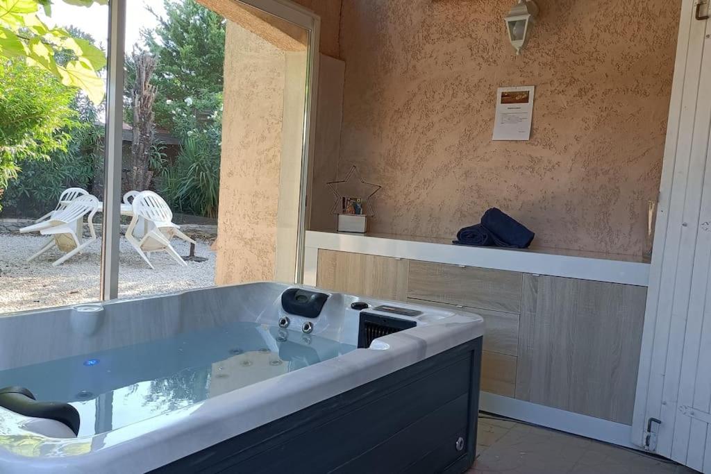 een groot bad in een kamer met een raam bij La Villamour avec jacuzzi in Gigean