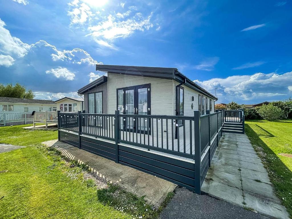 a tiny house with a black and white fence at Stunning Lodge With Decking Nearby Hunstanton Beach, Sleeps 6 Ref 23215k in Hunstanton