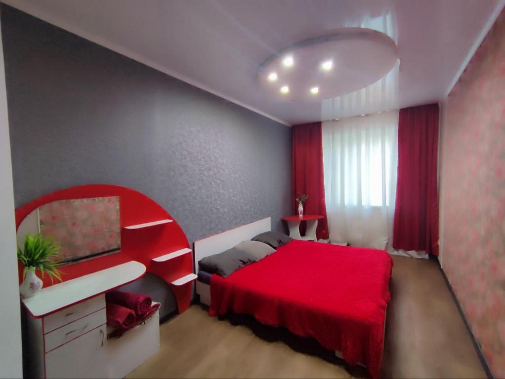 1 dormitorio con cama roja y escritorio en Апартаменты 2-х комнатные в Степногорске en Stepnogorsk