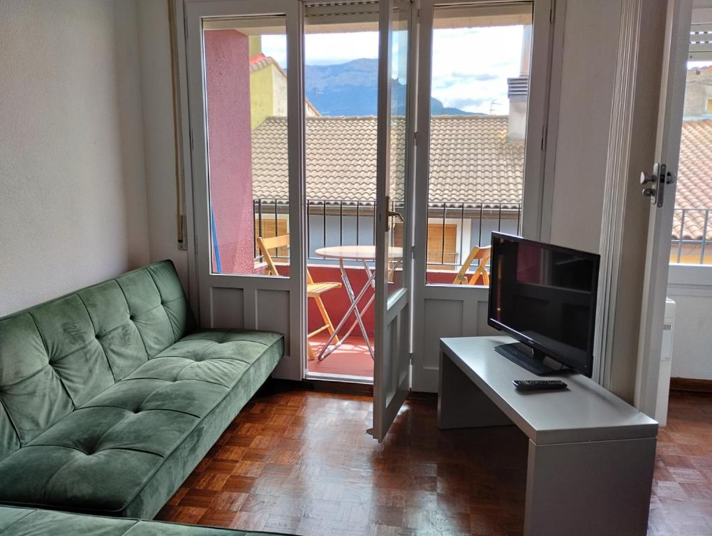 a living room with a couch and a flat screen tv at Luminoso, céntrico y silencioso apartamento in Jaca
