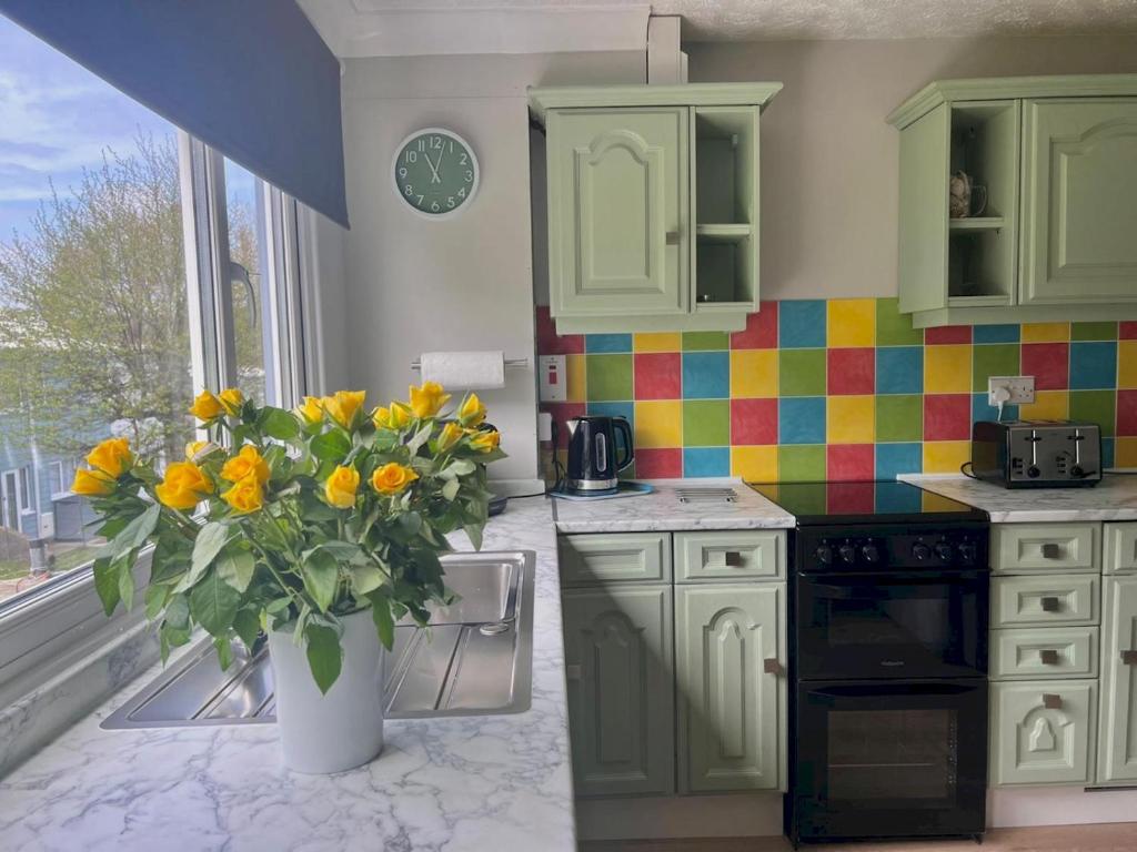 una cocina con un jarrón con flores amarillas. en Pass the Keys Seaside Escape Freshwater East en Pembroke