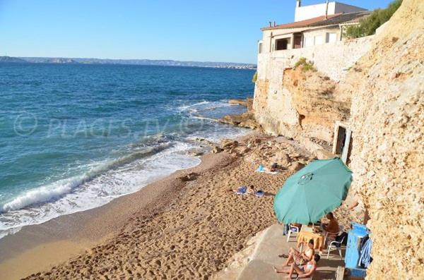 un groupe de personnes assises sur une plage avec un parasol dans l'établissement Appartement T2 en bord de mer, à Marseille