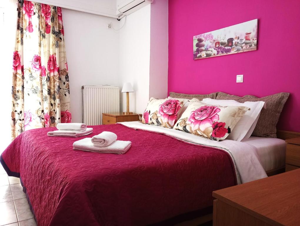 a bedroom with pink walls and a bed with towels on it at Nicholas House ! in Chalkida