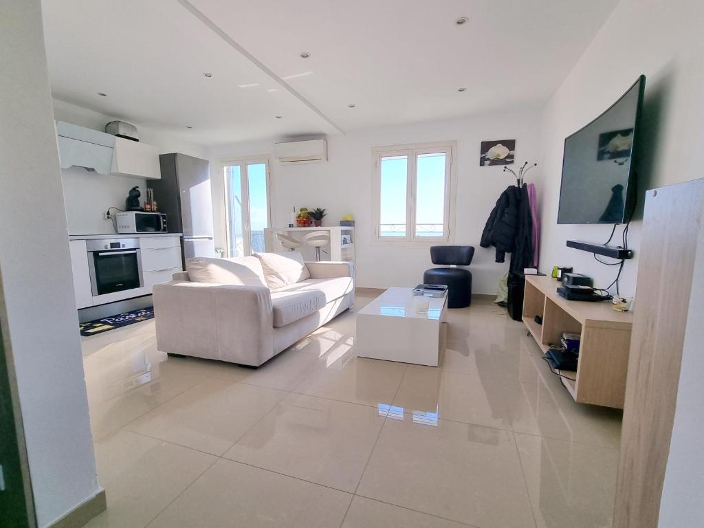 a white living room with a couch and a table at 2 pièces d’exception vue Mer in Vence