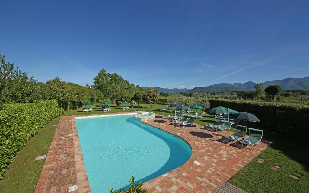 - une vue sur la piscine bordée de chaises et de parasols dans l'établissement Residence Il Melograno, à Manerba del Garda