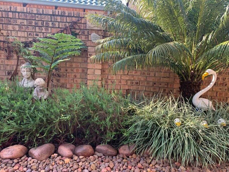 einen Garten mit Felsen und Pflanzen vor einer Ziegelwand in der Unterkunft Home away from Home in Pretoria