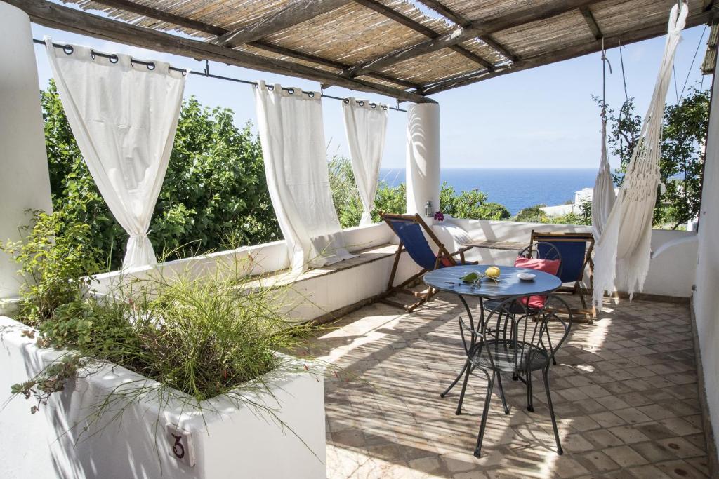 un patio con tavolo, sedie e vista sull'oceano di Il Gelso Vacanze a Malfa