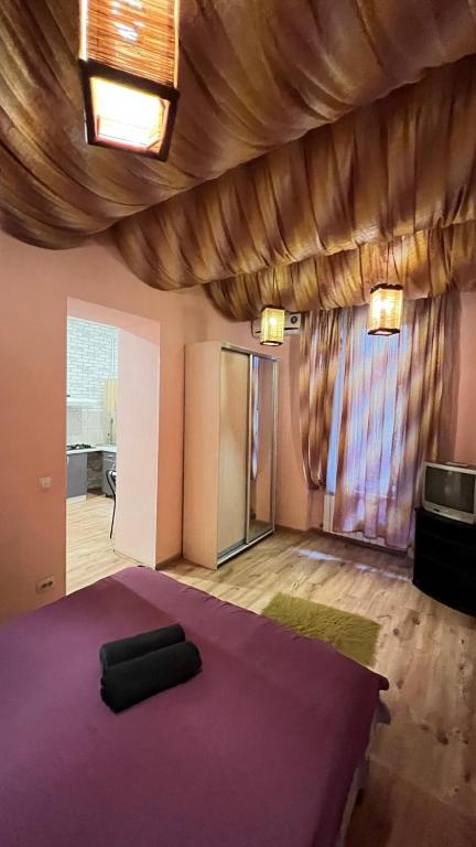 una camera con letto viola e pavimento in legno di 10/8 Kotliarska Moisha House a Lviv